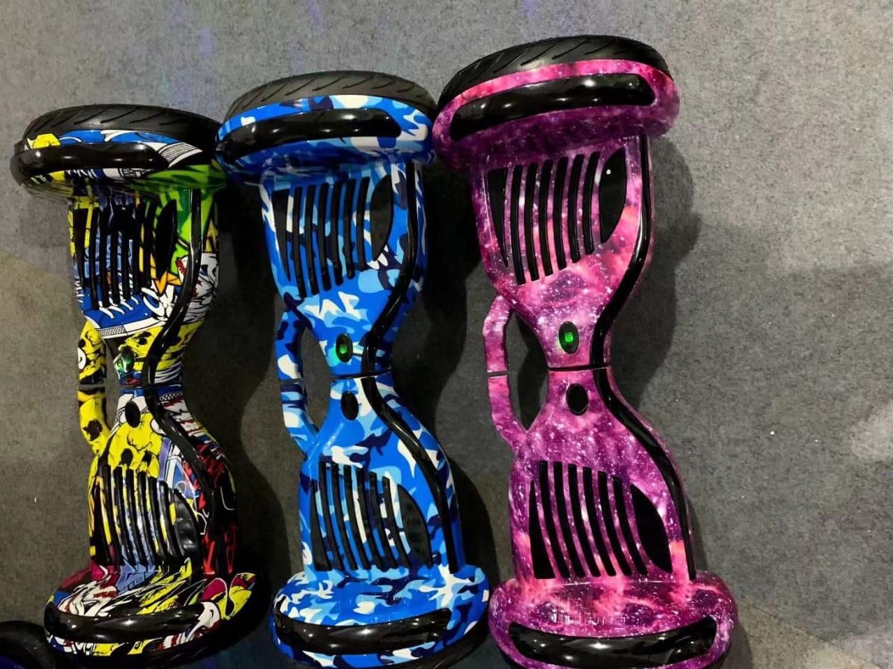 Three colorful 10 inch Balance wheel hoverboard for kids in yellow, blue, and pink designs on a gray floor