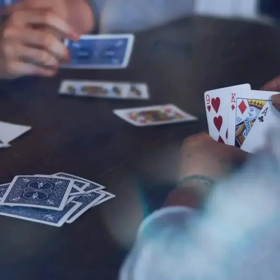 Close-up view of hands playing games of playing cards on a wooden table