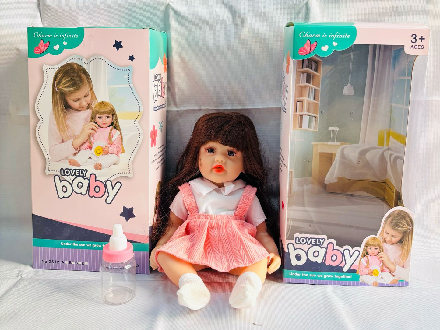 realistic baby doll with accessories silicone real Doll Ahmedabad . lifelike brown hair doll in pink dress with bottle
