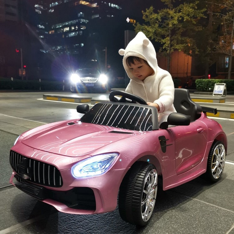 Child driving a pink remote control kids car 1-8 years on a city street at night