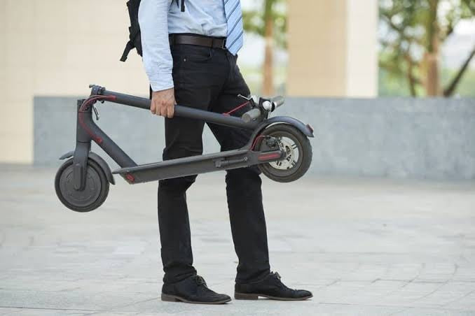 Foldable electric scooter for kids and all ages Ahmedabad Gujarat held by man in business attire