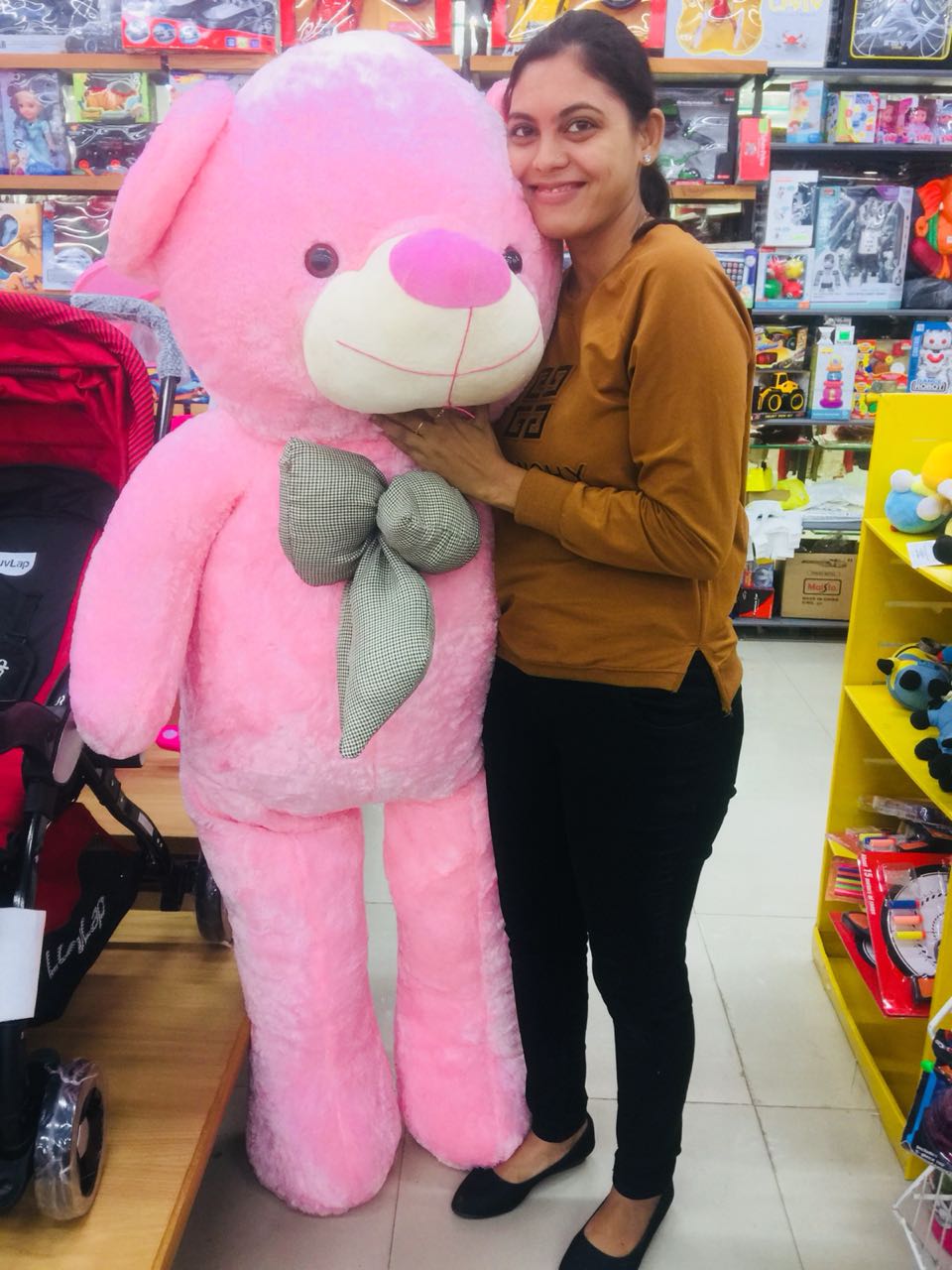 Woman hugging a giant pink plush with green bow in toy store big teddy bear In Ahmedabad Gujarat online India