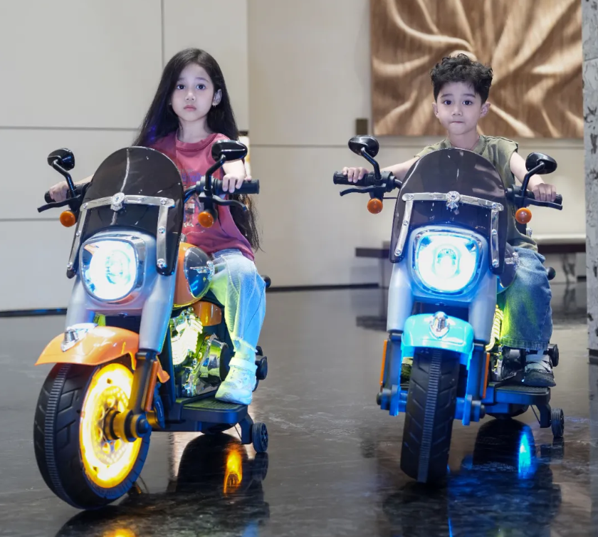 Two kids riding colorful battery operated bike for kids Ahmedabad with bright LED lights indoors