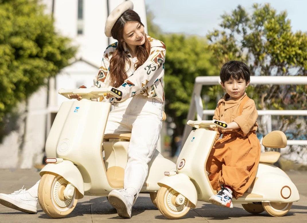 Battery operated kids scooter Ahmedabad Gujarat India with child and adult riding cream-colored scooters outdoors