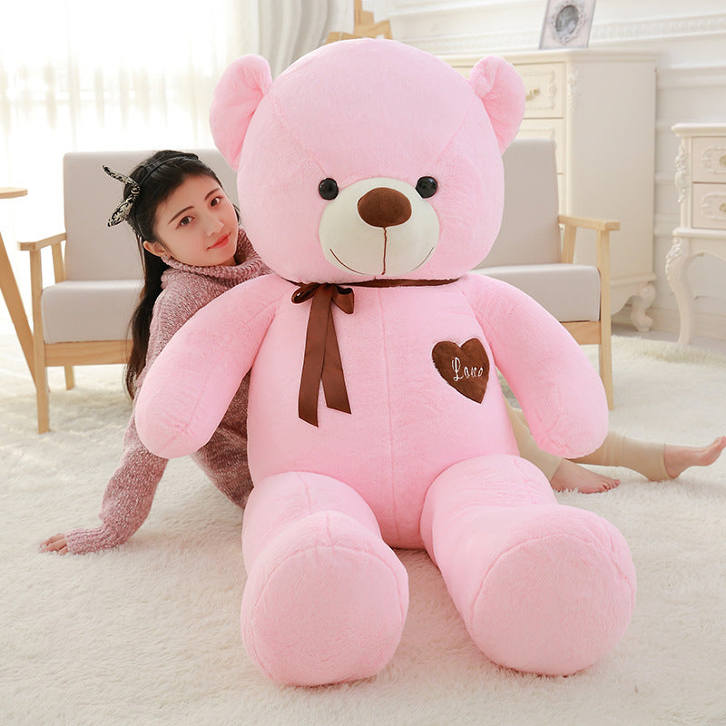 Pink large teddy bear with brown ribbon and heart patch with woman sitting behind buy big large teddy bear online Ahmedabad