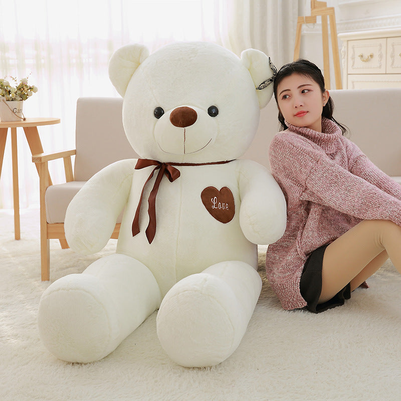 Buy big large teddy bear online Ahmedabad with a cream color and brown bow sitting next to a woman in a cozy room