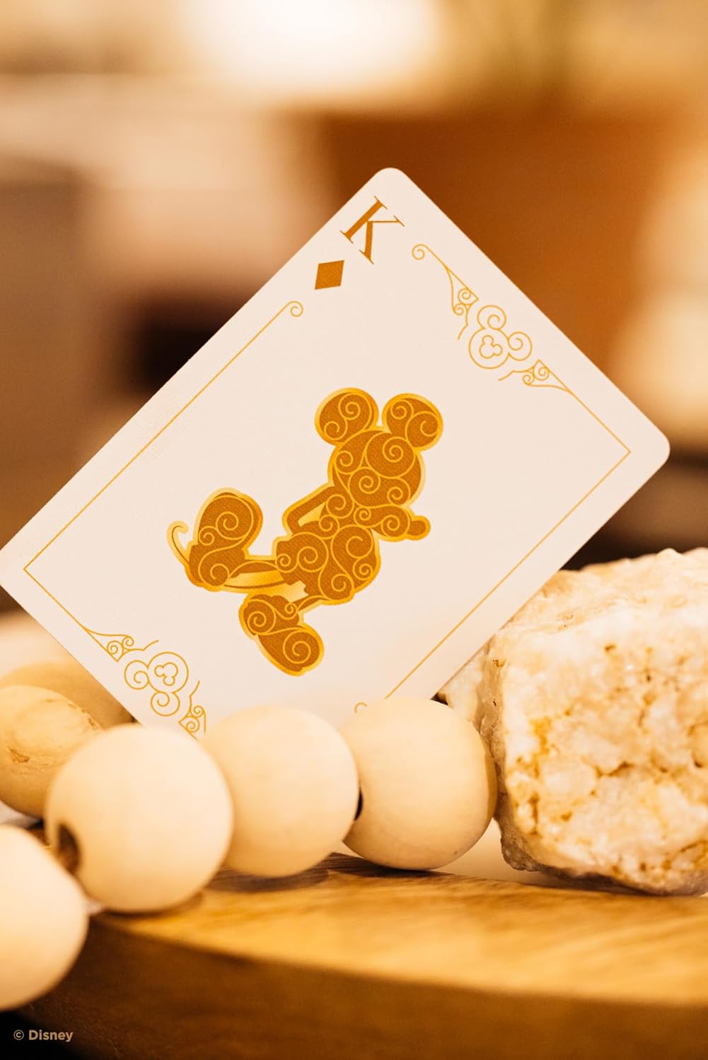 Mickey Mouse and Mickey Mouse Playing Cards featuring a gold design, displayed on a wooden surface