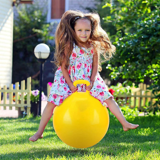 Young girl playing outdoor with yellow 75 cm bouncing ball with handle for kids zumba on grass