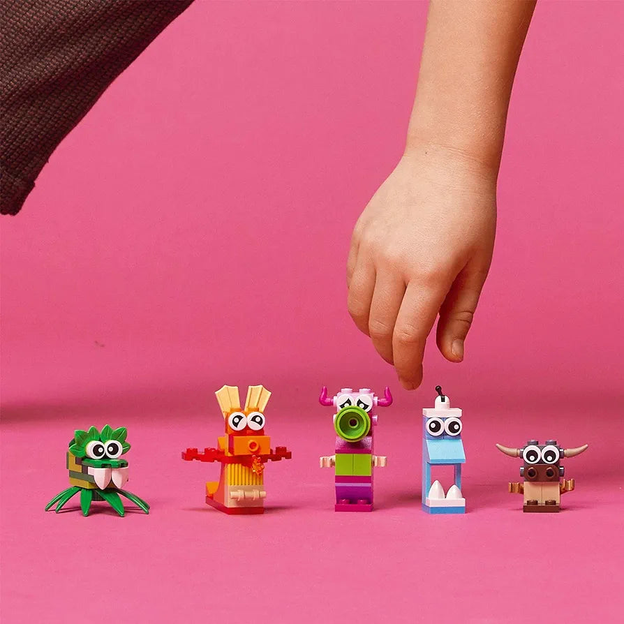 Child's hand interacting with colorful LEGO Classic Large Creative Brick Box 10698 characters for ages 4 and up at Sam's Toy World