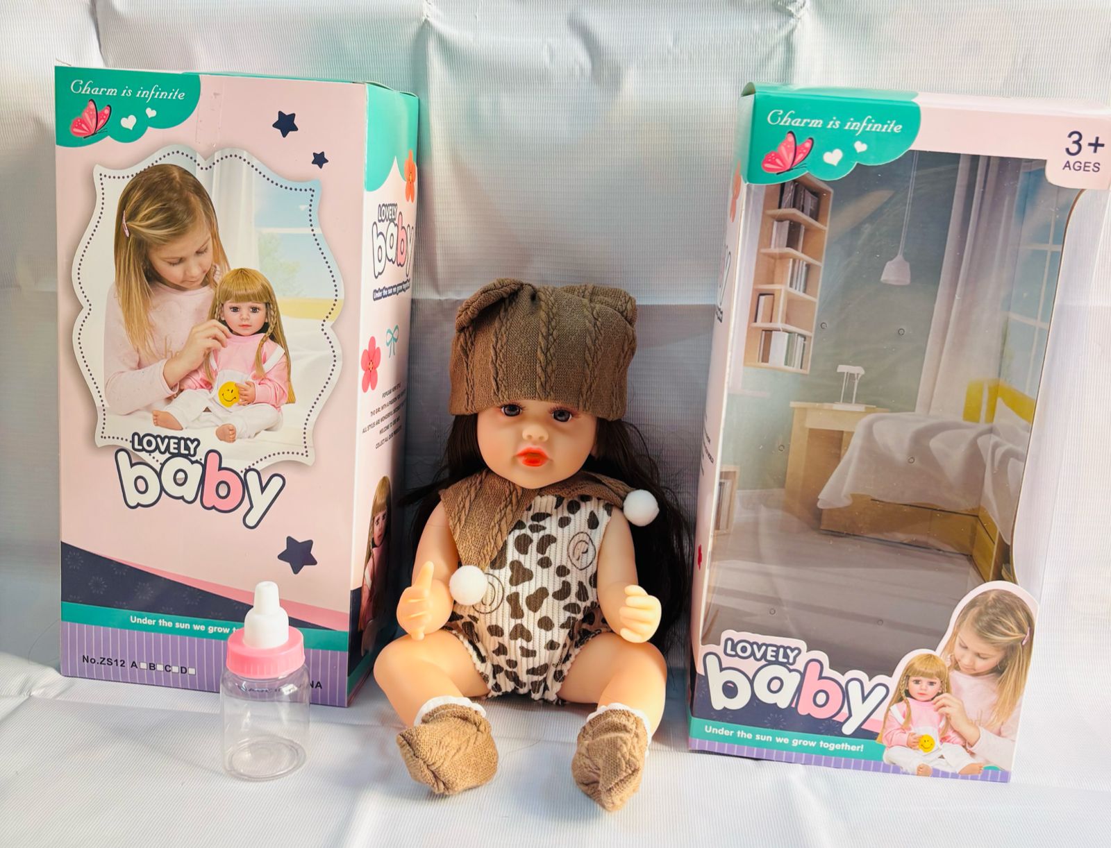 realistic baby doll with accessories silicone real Doll Ahmedabad . Lifelike doll in brown hat and romper with bottle and box
