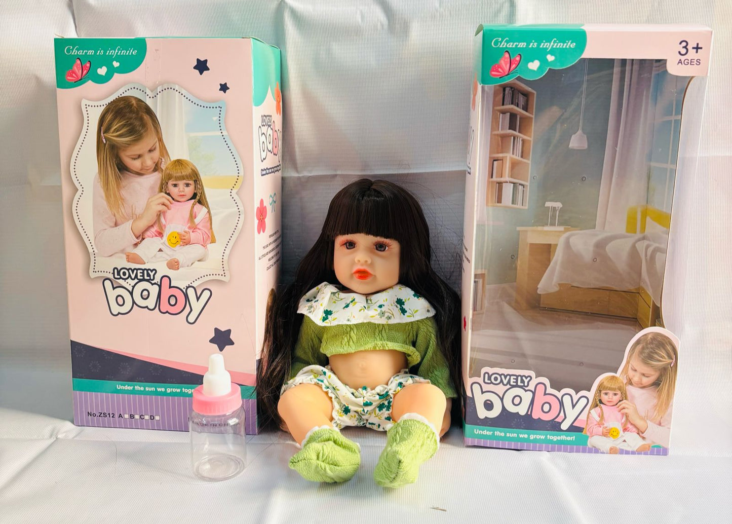 realistic baby doll with accessories silicone real Doll Ahmedabad . brown haired doll in green outfit with bottle and boxes