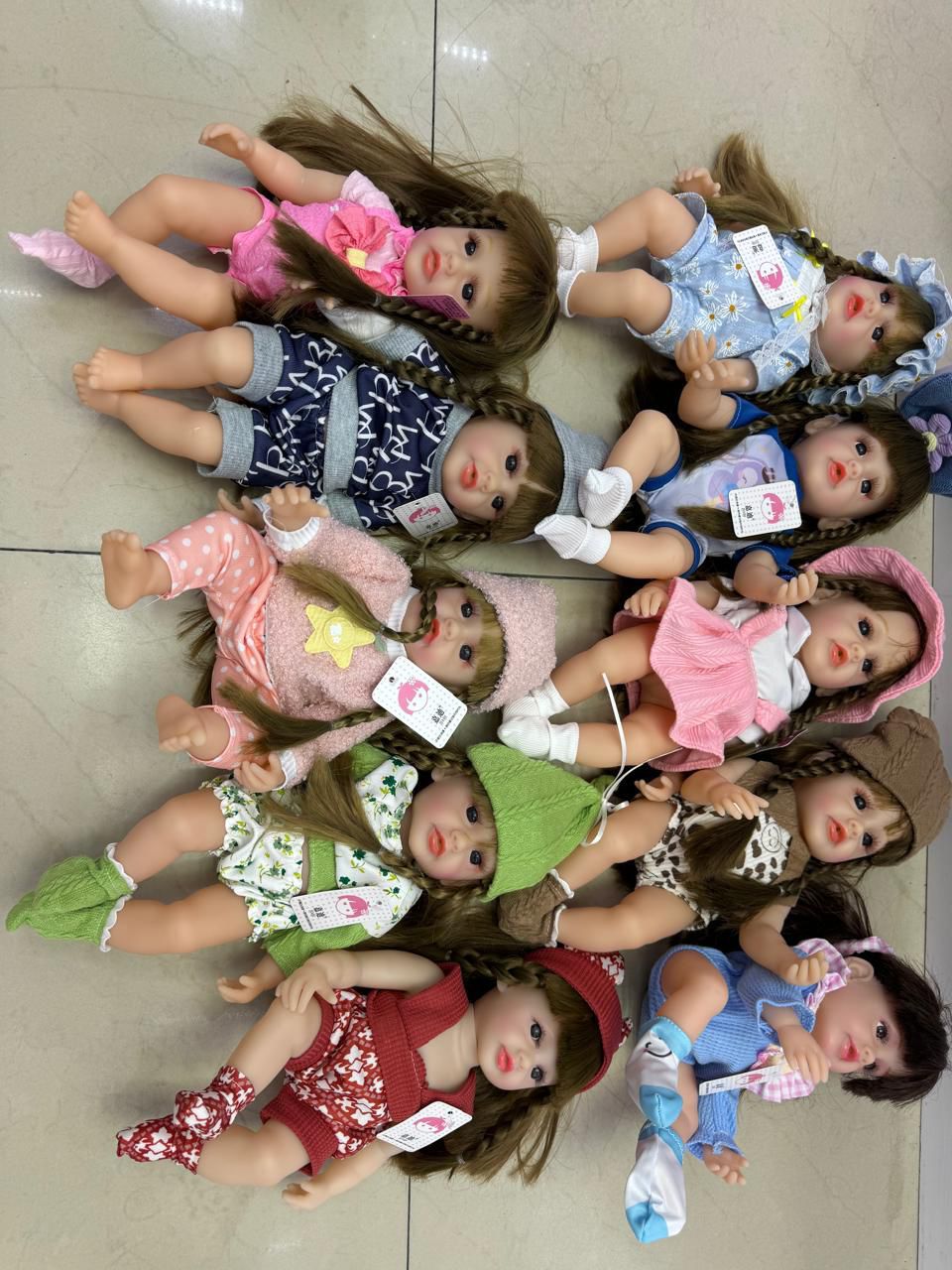Group of lifelike baby dolls in assorted outfits on tile floor realistic baby doll with accessories silicone real Doll Ahmedabad .